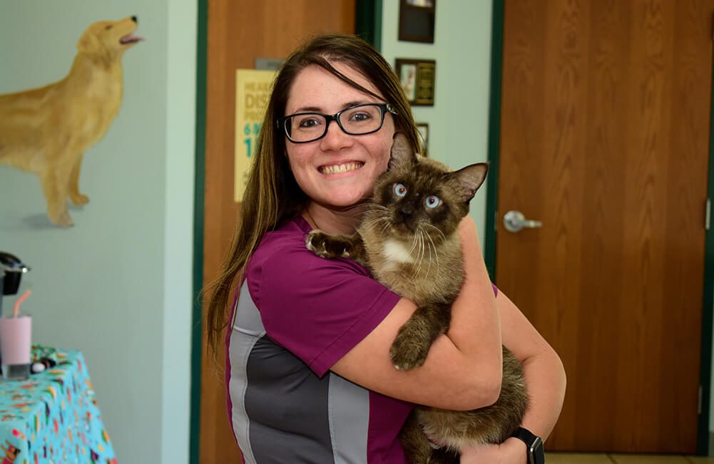 female vet tech holding cat and smiling