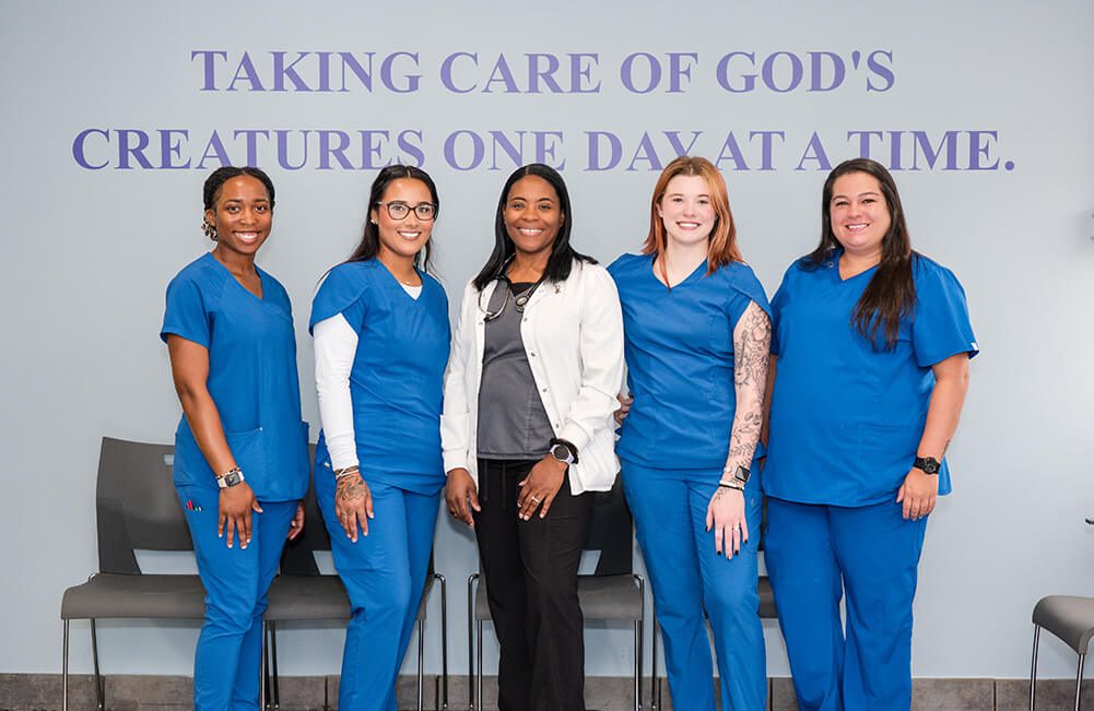 5 Members Of Vet Team Posing 5 Members Of Van Crest Animal Hospital posing for camera in front of slogan wall
